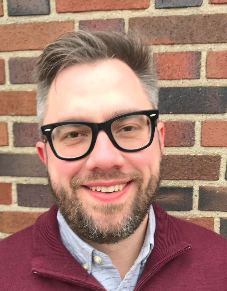 Andrew Wall, MA, LCPC, smiling in a maroon quarter-zip sweater